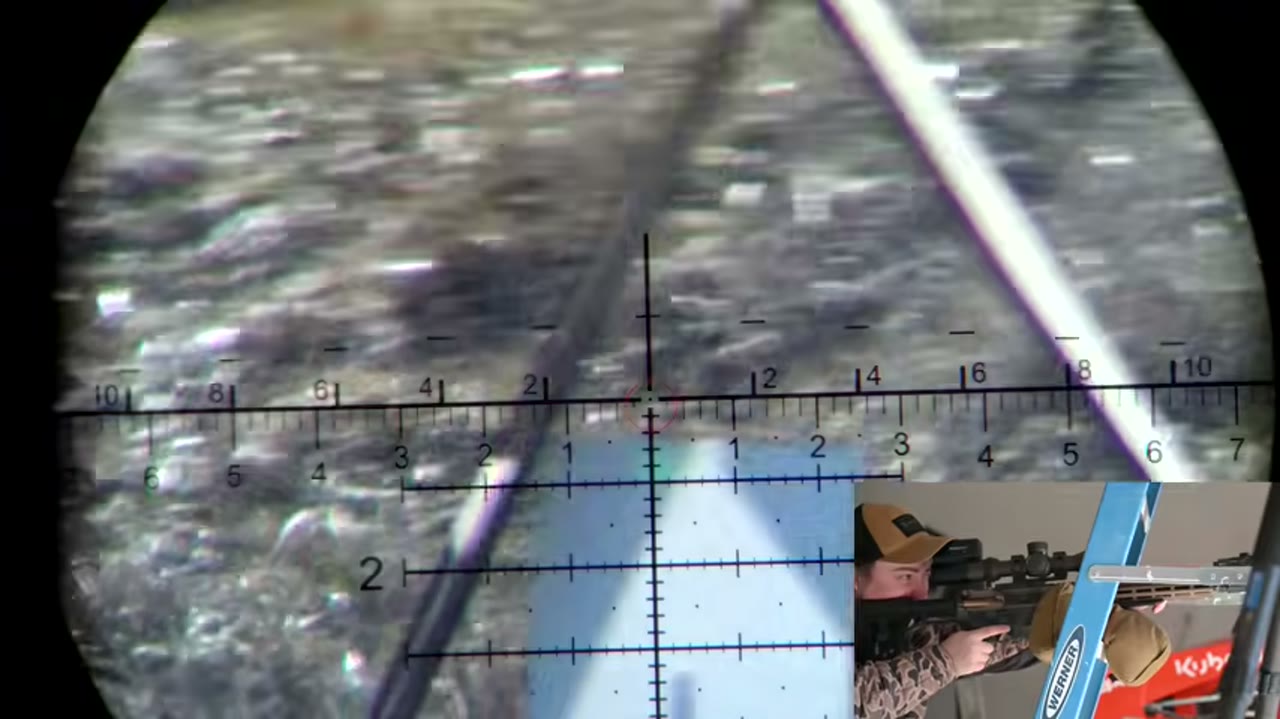 Through-the-scope view from RAD's test: a barrel-mounted laser plotted against a milliradian grid, with a picture-in-picture of the shooter loading the bipod.